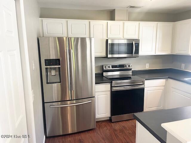 kitchen featuring stainless steel appliances, dark hardwood / wood-style floors, and white cabinets