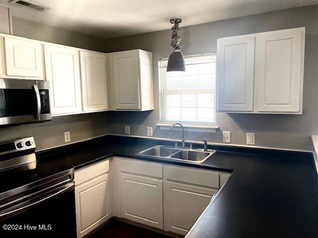 kitchen featuring white cabinets, sink, pendant lighting, and appliances with stainless steel finishes