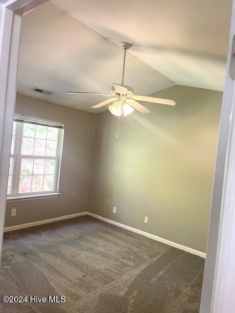 carpeted spare room with vaulted ceiling and ceiling fan