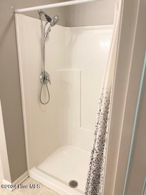 bathroom with a shower with shower curtain and tile patterned flooring