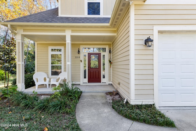 view of exterior entry featuring covered porch and a garage