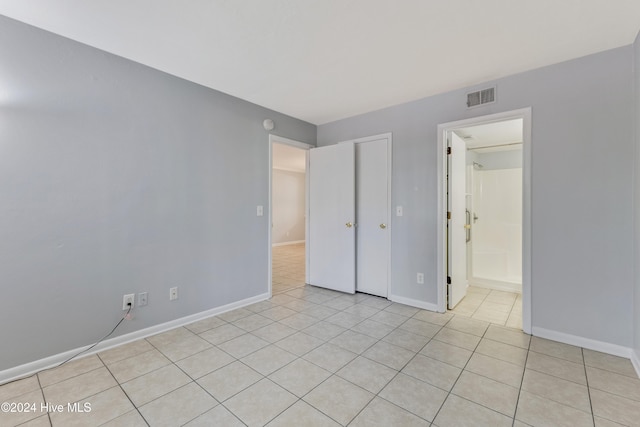 unfurnished bedroom with light tile patterned flooring and ensuite bath