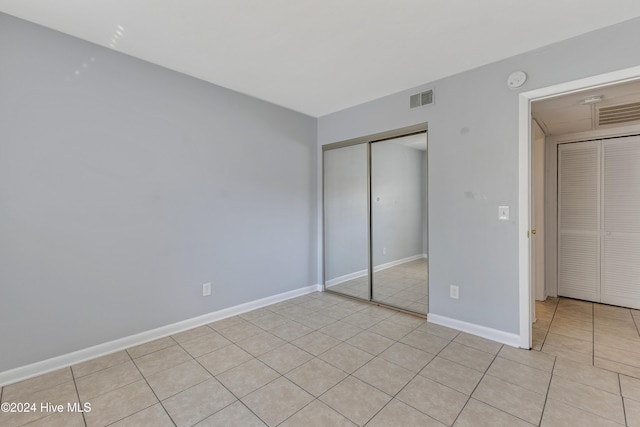 unfurnished bedroom with light tile patterned floors and a closet