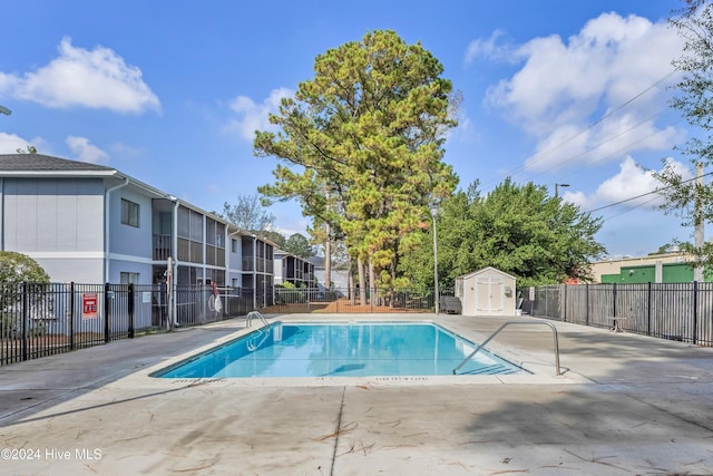 view of swimming pool featuring a patio area and a storage shed