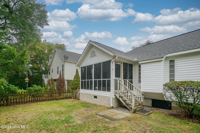 rear view of house with a yard and a sunroom