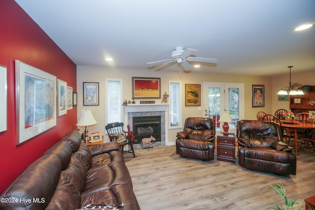 living room with ceiling fan, a tiled fireplace, and light hardwood / wood-style flooring