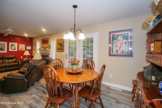 dining room with hardwood / wood-style floors and ceiling fan with notable chandelier