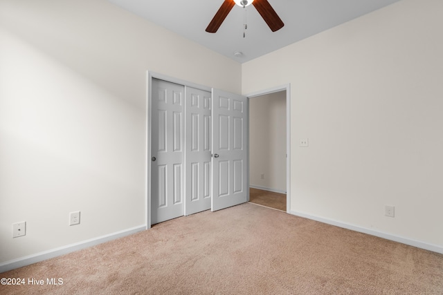 unfurnished bedroom featuring a closet, light colored carpet, and ceiling fan