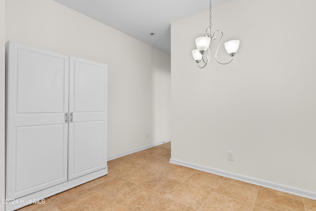 tiled empty room featuring an inviting chandelier