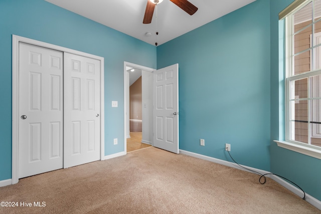 unfurnished bedroom featuring ceiling fan, a closet, and light colored carpet