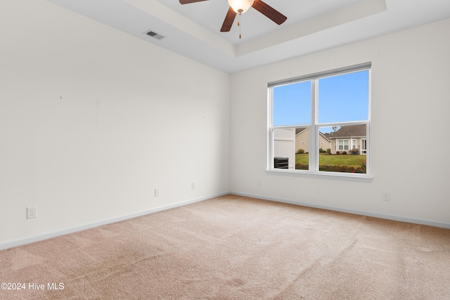 unfurnished room with ceiling fan, carpet flooring, and a raised ceiling