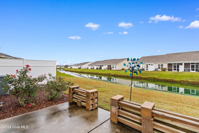 view of community featuring a lawn, a patio, and a water view