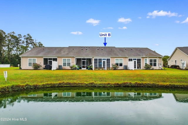 back of property featuring a water view and a lawn