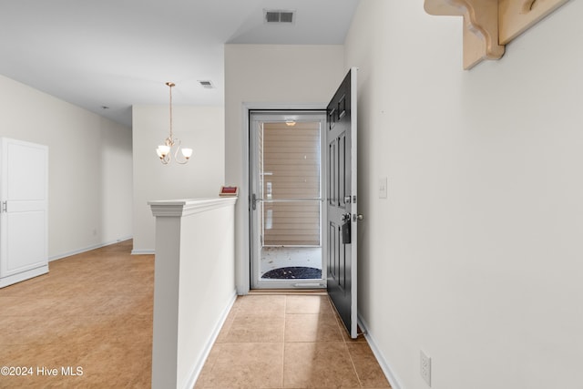 hallway with a chandelier and light tile patterned floors