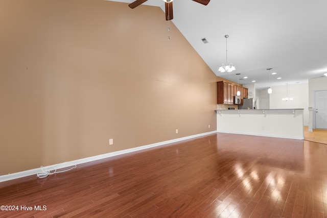 unfurnished living room featuring high vaulted ceiling, ceiling fan with notable chandelier, and wood-type flooring