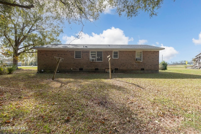 rear view of property with cooling unit and a yard