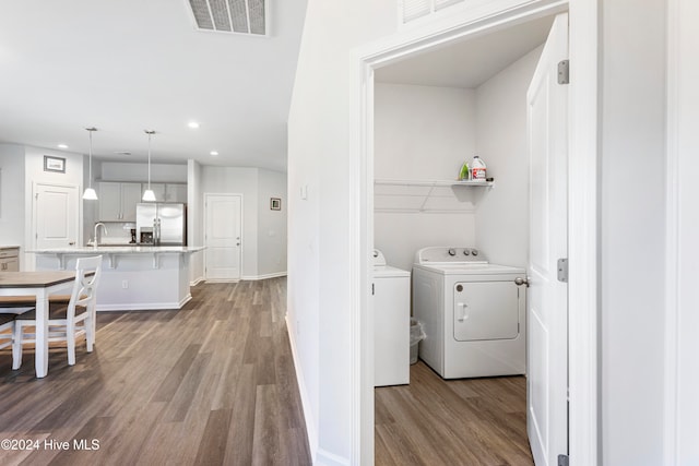 laundry room with wood-type flooring, sink, and washing machine and clothes dryer