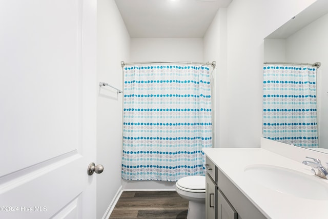 full bathroom with hardwood / wood-style flooring, shower / bath combo with shower curtain, vanity, and toilet