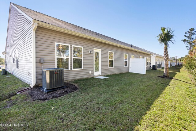 back of property featuring central AC unit and a yard