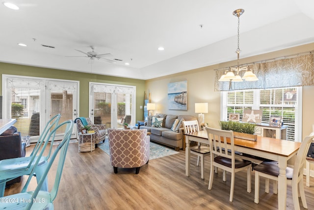 living room with ceiling fan with notable chandelier and light wood-type flooring