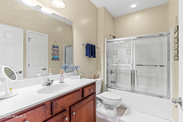 full bathroom with tile patterned flooring, vanity, toilet, and bath / shower combo with glass door