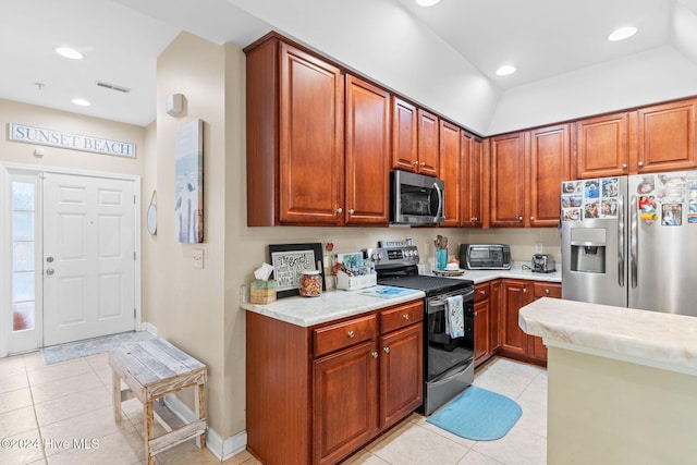 kitchen featuring light tile patterned floors, stainless steel appliances, and vaulted ceiling