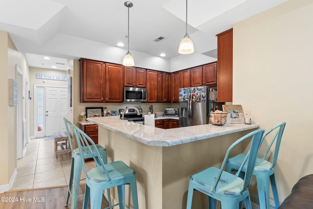 kitchen with a kitchen bar, kitchen peninsula, pendant lighting, and stainless steel appliances