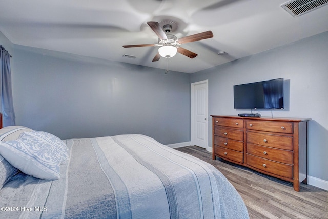 bedroom featuring visible vents, a ceiling fan, baseboards, and wood finished floors