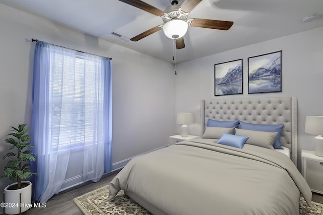 bedroom featuring ceiling fan, visible vents, baseboards, and wood finished floors