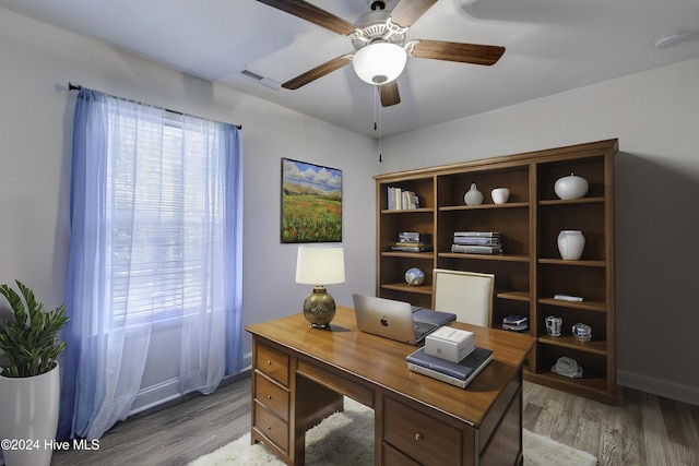 office area with light wood-type flooring, baseboards, visible vents, and ceiling fan