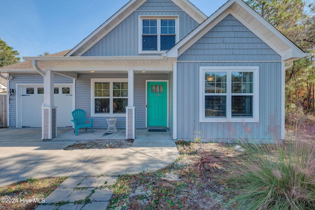 view of front facade featuring covered porch, board and batten siding, concrete driveway, and a garage