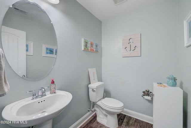 bathroom featuring visible vents, toilet, a sink, wood finished floors, and baseboards