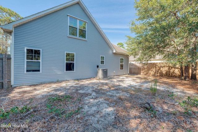 rear view of property featuring central air condition unit and fence