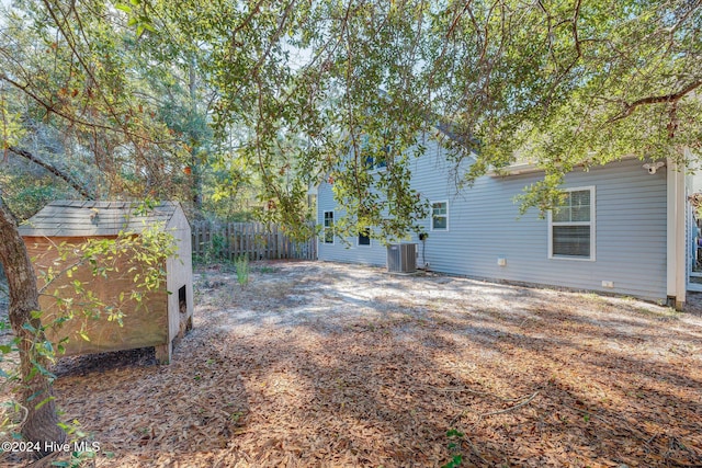 view of yard with fence, a shed, driveway, central AC, and an outdoor structure