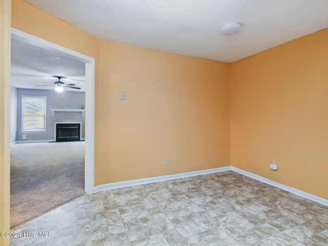 carpeted empty room with ceiling fan and a textured ceiling