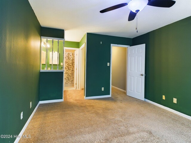 unfurnished bedroom with ceiling fan, light colored carpet, and ensuite bath