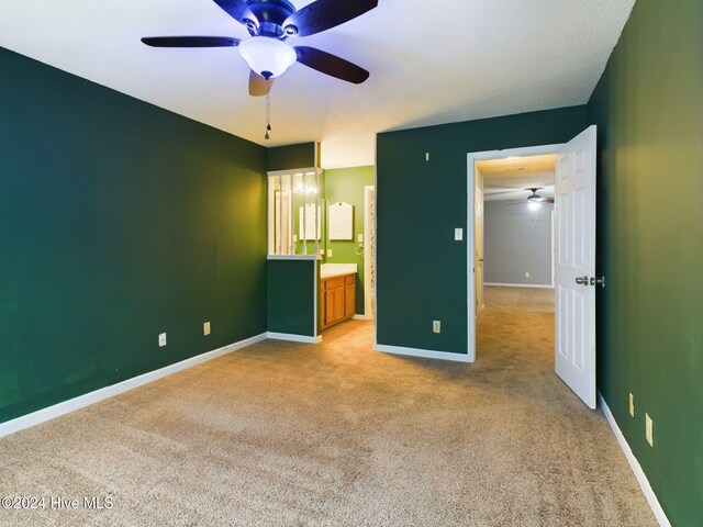 unfurnished bedroom with ensuite bathroom, ceiling fan, and light carpet