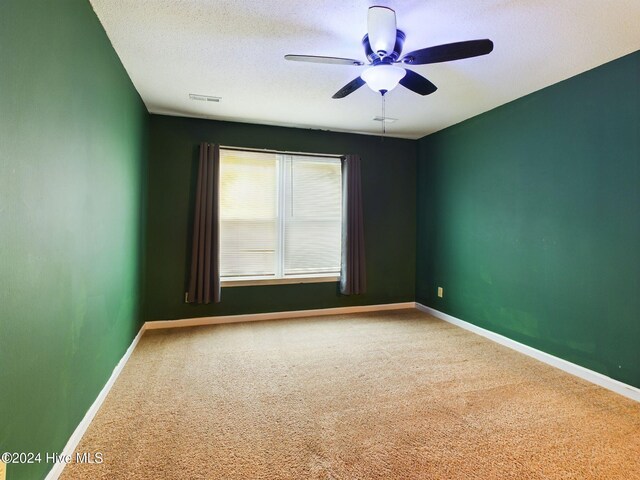 carpeted spare room with a textured ceiling and ceiling fan