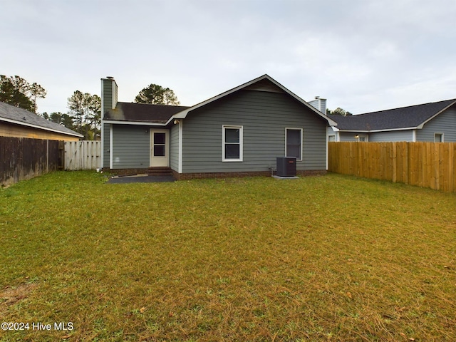 rear view of property with cooling unit and a yard