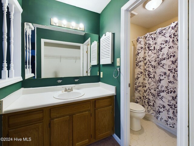 bathroom with vanity, curtained shower, toilet, and a textured ceiling