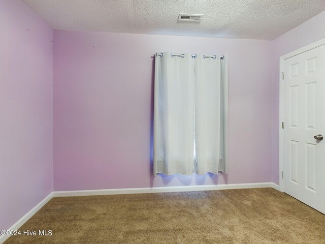 unfurnished room featuring carpet floors and a textured ceiling