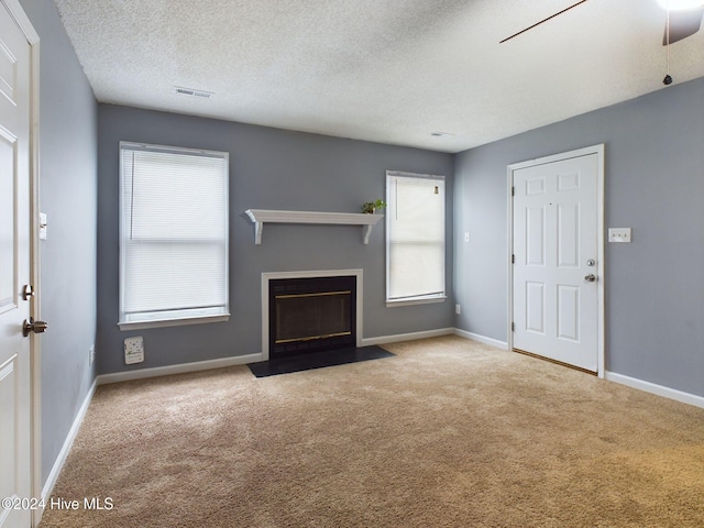 unfurnished living room featuring light carpet, a textured ceiling, and ceiling fan