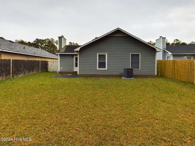 rear view of property with cooling unit and a lawn