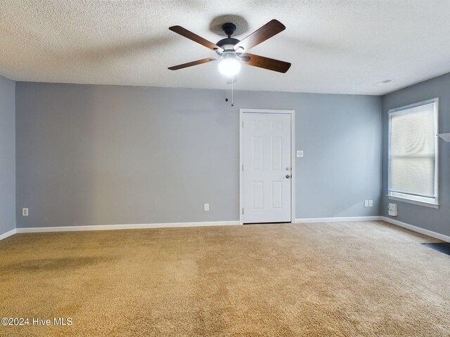 unfurnished room with carpet, ceiling fan, and a textured ceiling