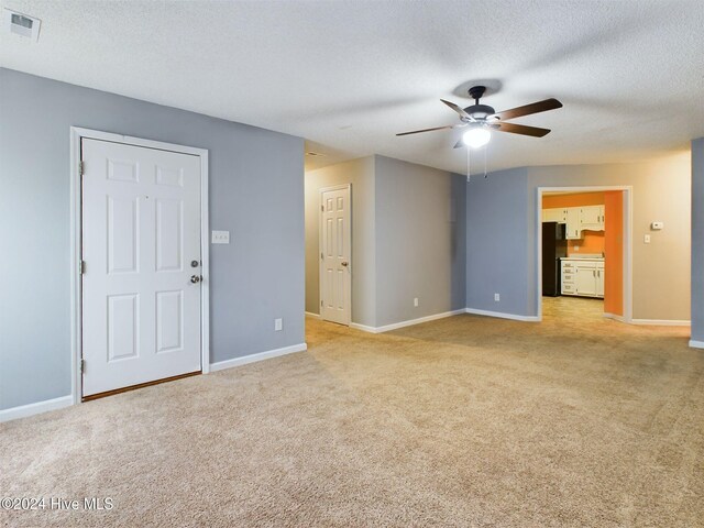 unfurnished living room featuring ceiling fan, light colored carpet, and a textured ceiling