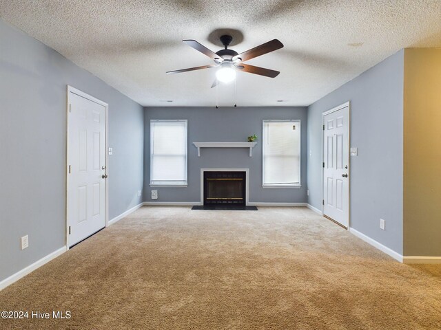 unfurnished living room with ceiling fan, light colored carpet, and a textured ceiling