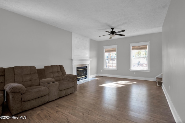 living room featuring a fireplace, ceiling fan, a textured ceiling, and dark hardwood / wood-style flooring