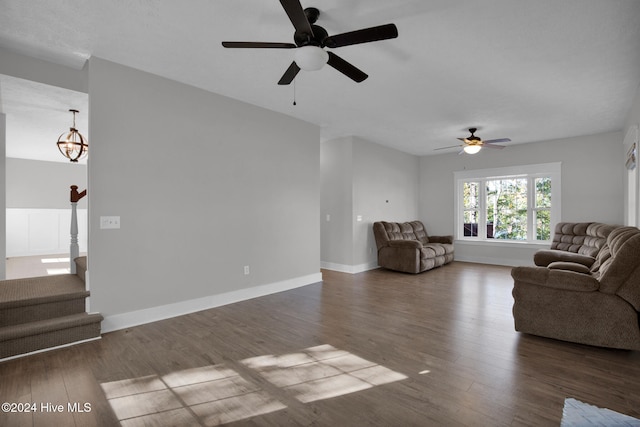 unfurnished living room featuring dark hardwood / wood-style floors and ceiling fan with notable chandelier