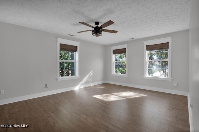 unfurnished room featuring a textured ceiling, dark hardwood / wood-style flooring, and a healthy amount of sunlight