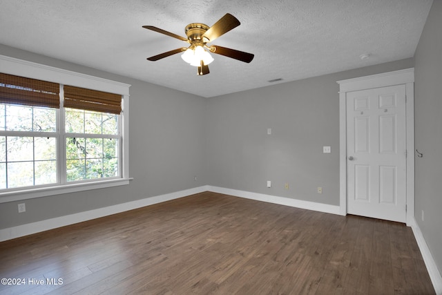 empty room featuring dark wood-type flooring, a textured ceiling, and ceiling fan